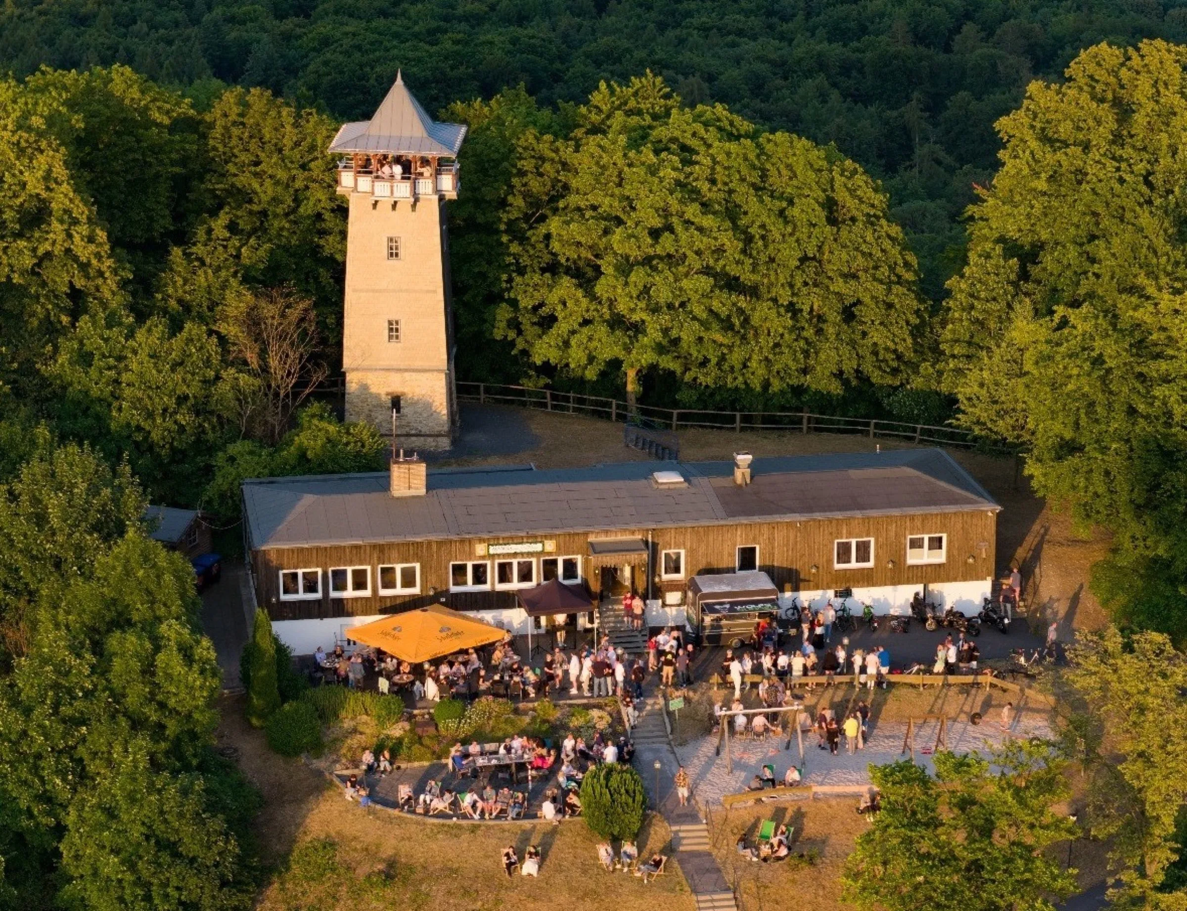 Luftaufnahme des Ausblick am Wieterturm mit historischem Turm, Gebäude und Wald im Abendlicht